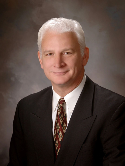 A man in suit and tie with white hair.