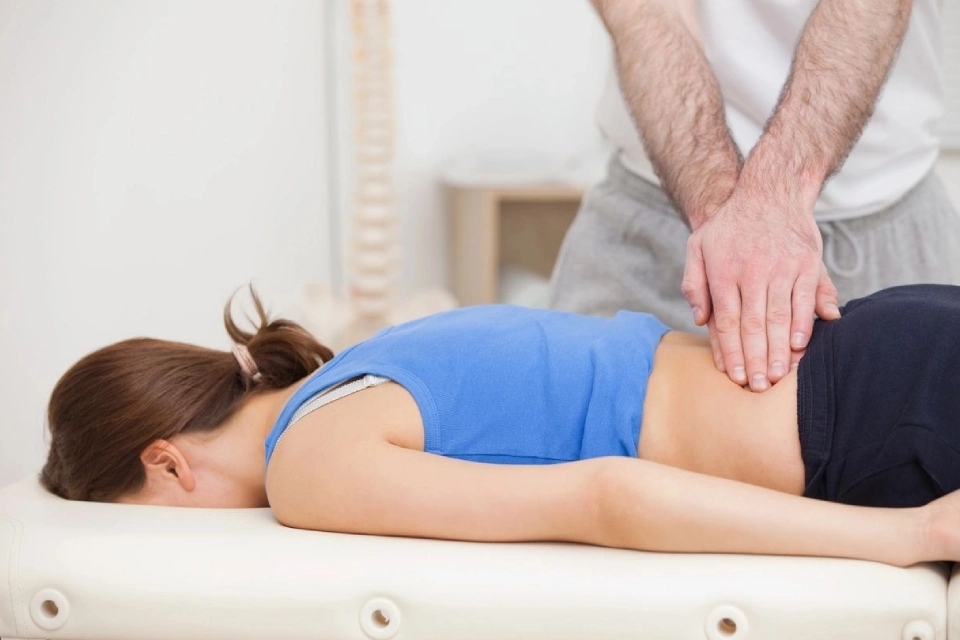 A person is getting their back examined by an osteopath.